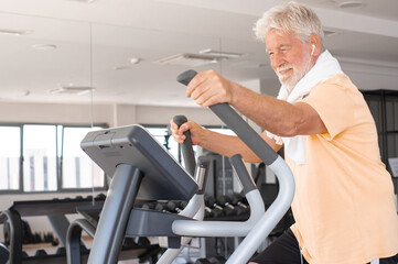 Attractive smiling retired man excercising on stepper at gym to stay fit. Cardio excercises for mature people. Athleticspirit concept