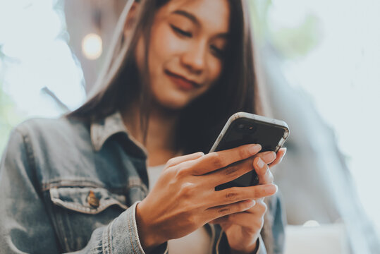 Close-up Image Of Young Asian Woman Sitting At Cozy Cafe And Using Modern Smartphone Device, Female Hands Typing Text Message Via Cellphone