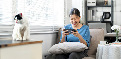 Happy relaxed young woman sitting on couch using cell phone,  enjoying doing online ecommerce...