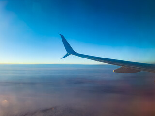 view from the airplane window to the blue sky and clouds and airplane wing
