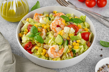 Shrimp salad with vegetables and olive oil mustard dressing. Fresh seafood salad in a bowl on a gray concrete background. Healthy food. Copy space.