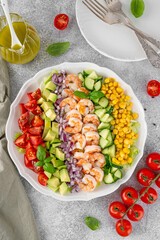 Shrimp salad with vegetables and olive oil mustard dressing. Fresh seafood salad on a white plate on a gray concrete background. Healthy food. Copy space.