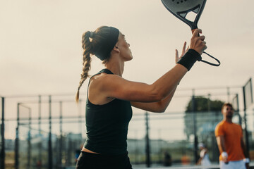 Female padel athlete raising her racket with a firm grip, preparing to hit a smash