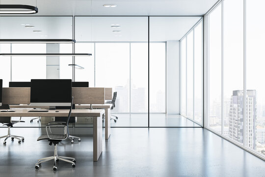 Contemporary glass coworking office interior with panoramic windows and city view, furniture, equipment and computer monitors. 3D Rendering.