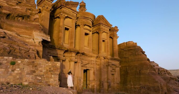 Woman Admiring Iconic Monastery Ad Deir In Ancient City Of Petra At Sunset. drone arc shot