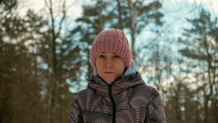 Portrait of a young woman of natural beauty in warm clothes in a winter forest.