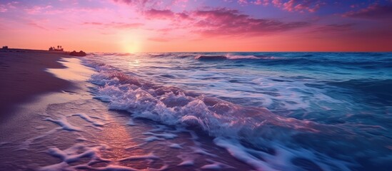 The colorful sunset is seen from the blue, pink sea beach with the waves gently flowing onto the shore