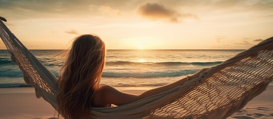 Young woman relaxing in a hammock on a sandy beach enjoying the sunset over the waves of the Indian ocean - obrazy, fototapety, plakaty