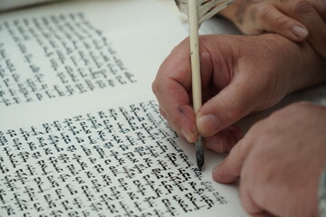 hand writing of a Jewish Torah scroll with a quill or feather according to ancient Jewish tradition.