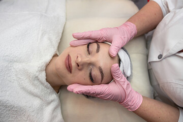 Fototapeta na wymiar Closeup of young beautiful woman receiving Anti-aging facial massage in spa center