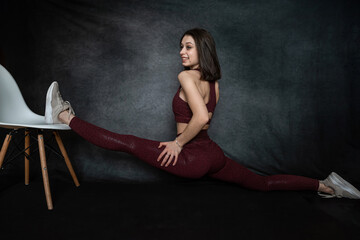 Fitness female trainer demonstrates how to do it right splits in dark black background