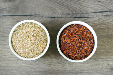 Red and white quinoa on the two white plates on the wooden background. Healthy food and nutrition concept. Safe, ecological, and healthy products