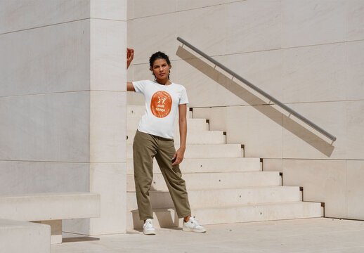 Mockup of woman wearing customizable t-shirt, standing by steps