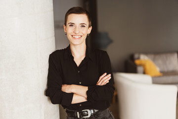 Laughing Young Woman with Short Hair Leaning Against Wall in Modern Living Room