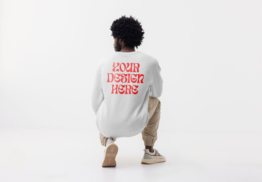 Mockup of man wearing customizable sweatshirt crouching in studio