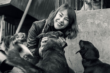 Dog in a shelter. An animal shelter volunteer takes care of dogs. A volunteer takes care of a dog at a shelter. Black white image