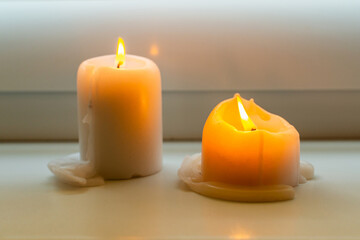 Two burning candles on windowsill.Two candles on a windowsill at home interior.Closeup.