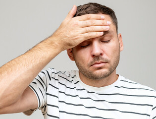 Portrait of a man feeling unwell. Headache and fever. Man touches his forehead with his hand. - obrazy, fototapety, plakaty