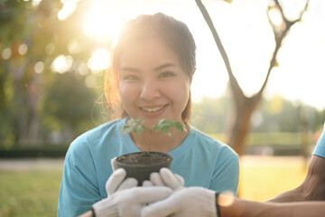 Portrait of female volunteer holding pot with green pant and smiling cheerfully. Charity and ecology concept