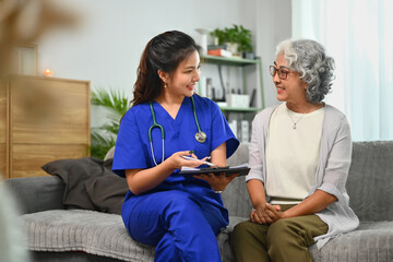 Female doctor showing positive test results to senior woman patient during home visit