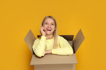 A young girl sits in a cardboard box