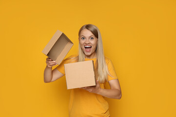 An attractive blonde looks into a cardboard box - obrazy, fototapety, plakaty