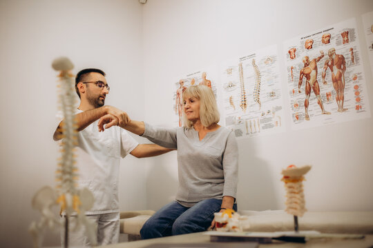 Happy senior woman lying on exam couch while chiropractor, osteopath or physiotherapy specialist is examining her leg and knee. Osteoporosis treatment, physical therapy, remedial exercise concept