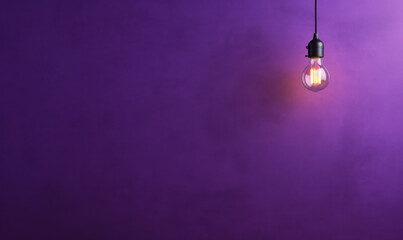 arrière plan violet uni avec une ampoule allumée qui pend - obrazy, fototapety, plakaty