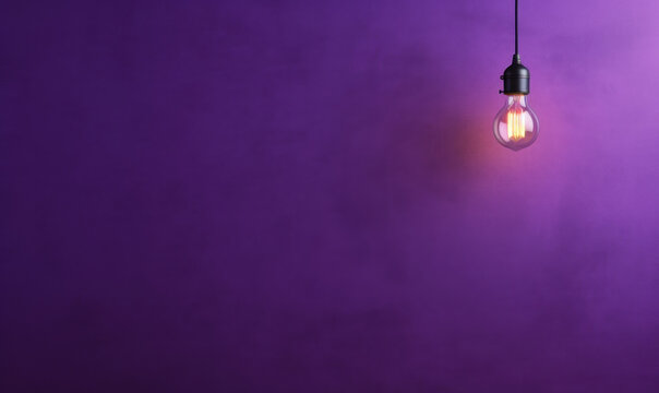 arrière plan violet uni avec une ampoule allumée qui pend