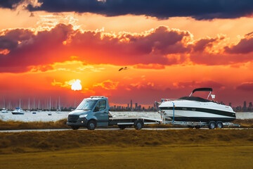 Luxury Boat Journey on the Road. Light-duty truck is hauling a Luxury Motor Boat at Sunset....