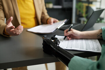 Close-up of woman with prosthetic arm filing medical documents during meeting with consultant in office