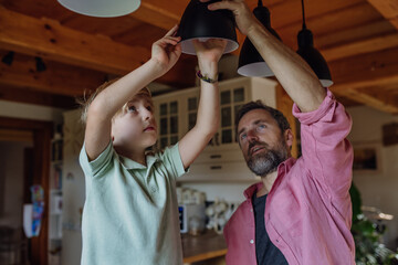 Father explaining led bubls to son, teaching him about energy efficiency, longevitiy and...