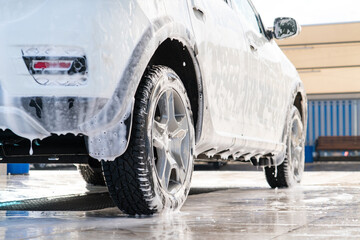 Self service high pressure car wash. Vehicle covered with foam - obrazy, fototapety, plakaty