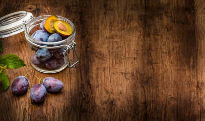 plums in a bottle on a wooden table