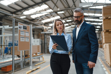 Female warehouse manager talking with logistics employee in warehouse, planning transport of...