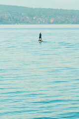 Unrecognizable person stand-up paddle boarding at Adriatic sea Kvarner gulf seen from the Crikvenica town coastline