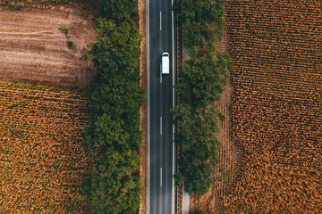 White commercial van vehicle driving along the highway road through countryside landscape, aerial...