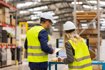 Female engineer and male supervisor standing in modern industrial factory, talking about...