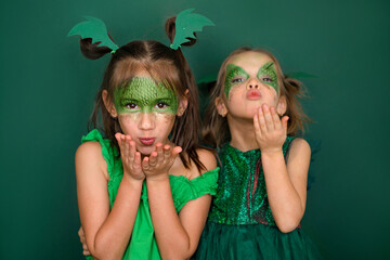 Beautiful girls with makeup in the guise of a green dragon are blowing kisses while waiting for the...