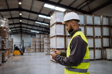 Warehouseman with tablet checking delivery, stock in warehouse. Warehouse manager using warehouse...