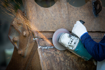 Hands of worker grinding a piece of metal,Grinding steel, Sparks from the grinding wheel.