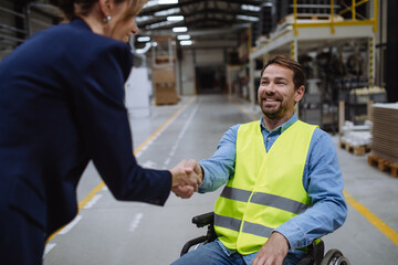 Portrait of man in wheelchair working in warehouse, shaking hand with HR manager, director. Concept of workers with disabilities, accessible workplace for employees with mobility impairment. - obrazy, fototapety, plakaty