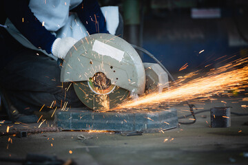 Heavy Industry Engineering Factory Interior with Industrial Worker Using Angle Grinder and Cutting a Metal Tube. Cutting metal and steel with a combination circular saw with a sharp round blade. - obrazy, fototapety, plakaty