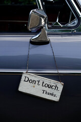 Donâ€™t touch sign haning on the side window of old car