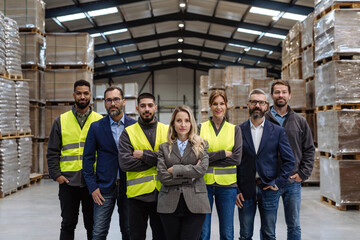 Full team of warehouse employees standing in warehouse. Team of workers, managers, female director in modern industrial factory, heavy industry, manufactrury. - obrazy, fototapety, plakaty