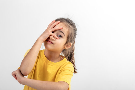 A little girl holds her palm on her face on a white background isolated.