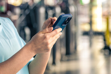 Woman using smartphone in fitness gym, close up.