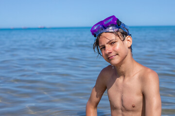 Teenager exudes positivity, wearing a diving mask while enjoying the vibrant atmosphere of a summer beach,copyspace.