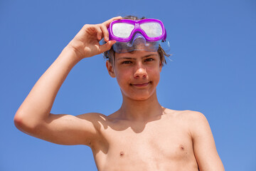 Handsome teenager smiles with a diving mask, embracing the warmth of a perfect summer day,bottom view.