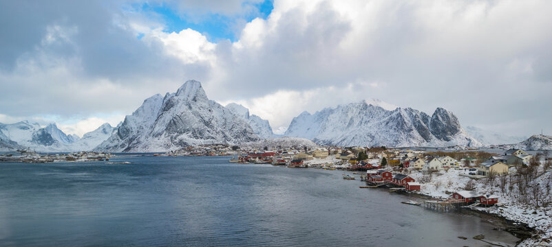 panorama of Norwegian fjords with mountain peaks with snow and red houses